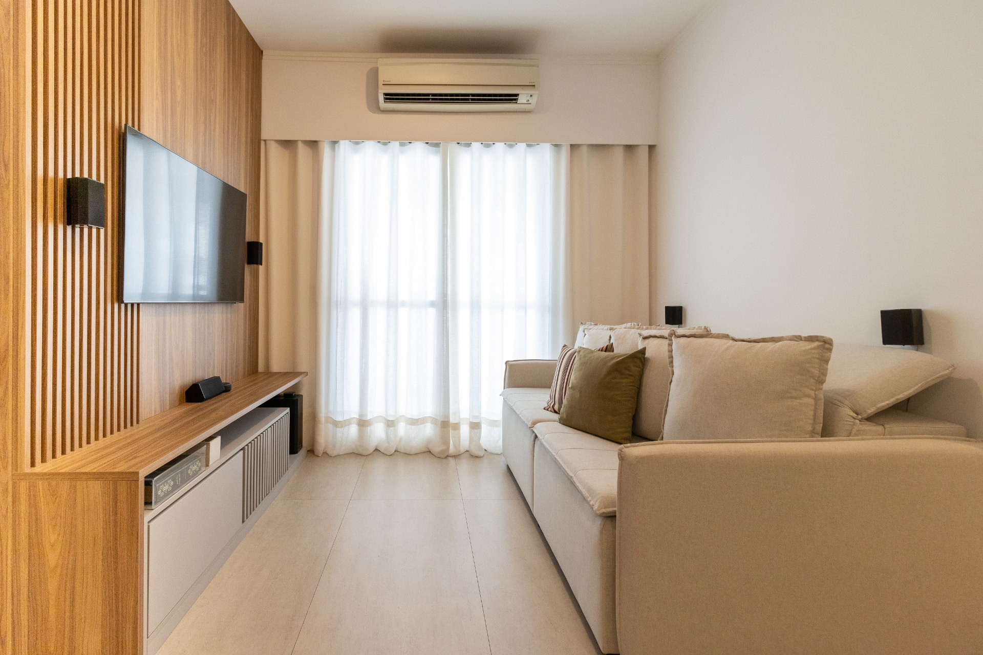 Sala com painel de TV e marcenaria em madeira natural